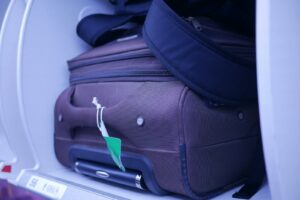 Close-up of luggage in an airplane's overhead compartment, showcasing travel essentials.