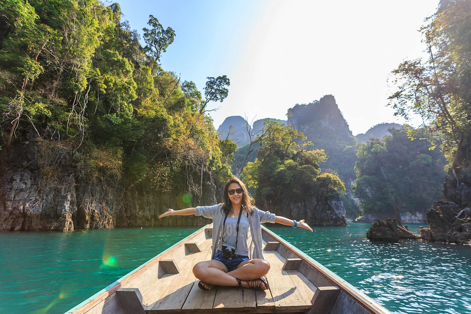 Asian woman relishing a serene boat journey through the lush karst landscape of Thailand's Khlong Sok.