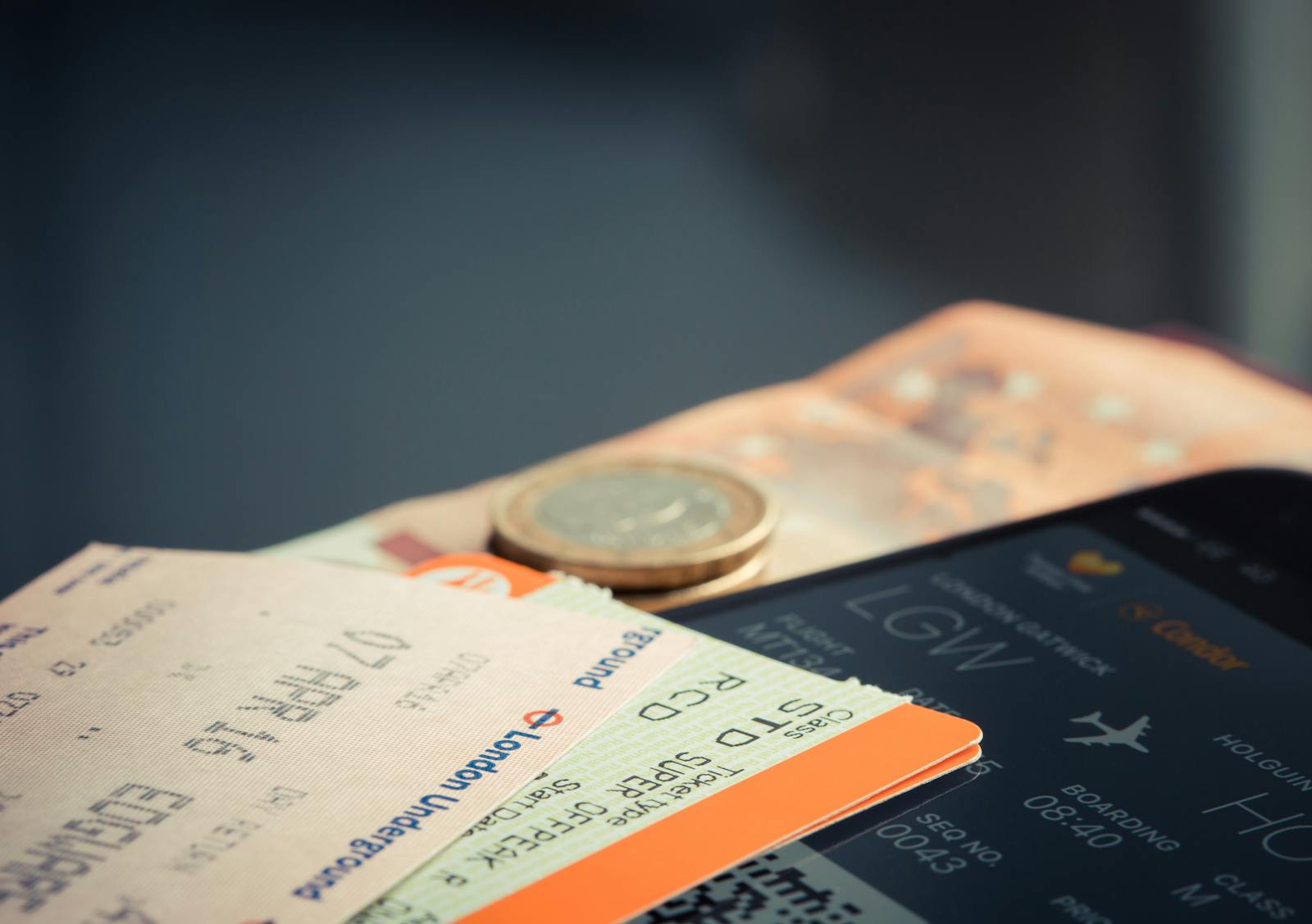 Airline ticket with euro coins and smartphone displaying flight details.