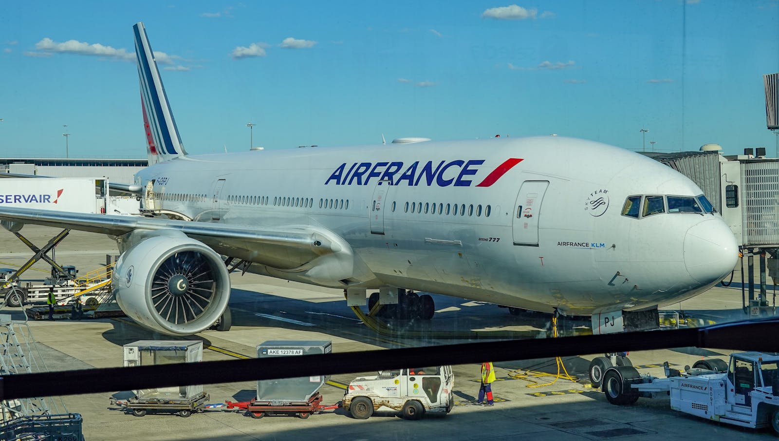 Air France airplane parked on the tarmac at an airport terminal under a clear blue sky.