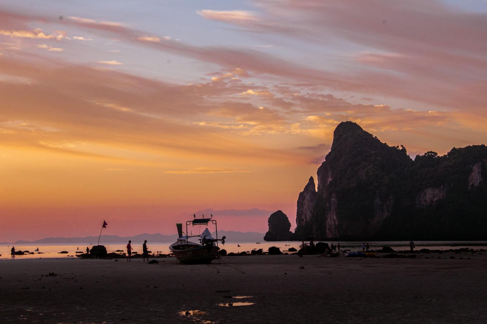 A vibrant sunset over the Phi Phi Islands beach with boats and stunning cliffs.